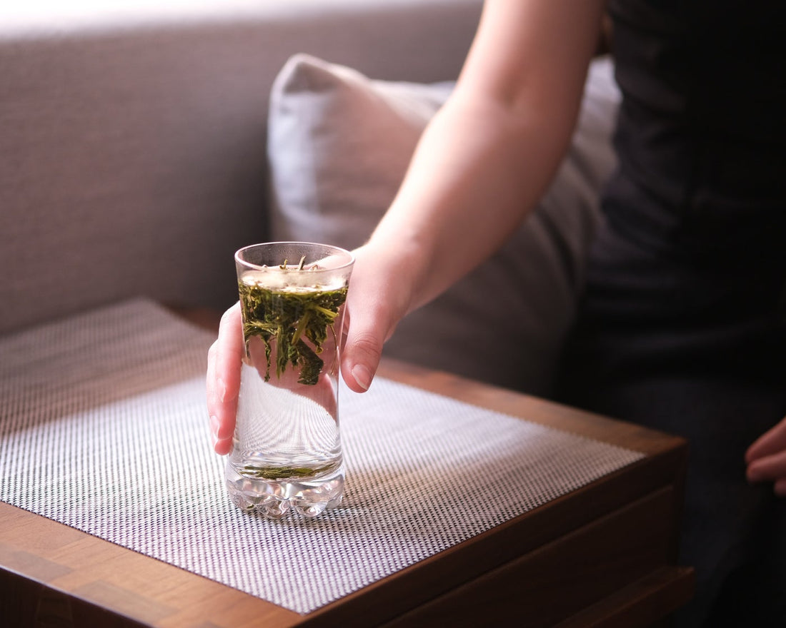Chinese green tea Taipinghoukui long loose-leaf in tall glass cup tumbler with girls hand