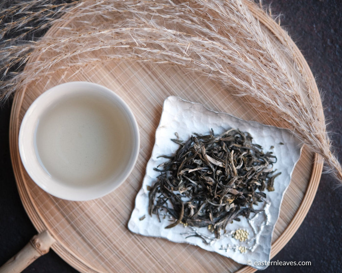 Jasmin green tea Chinese in loose-leaf, scented in high quality processing, infusion liquor in white ceramic cup, on silver tray and bamboo