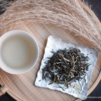 Jasmin green tea Chinese in loose-leaf, scented in high quality processing, infusion liquor in white ceramic cup, on silver tray and bamboo