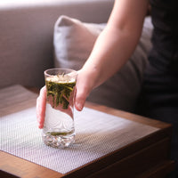 Chinese green tea Taipinghoukui long loose-leaf in tall glass cup tumbler with girls hand