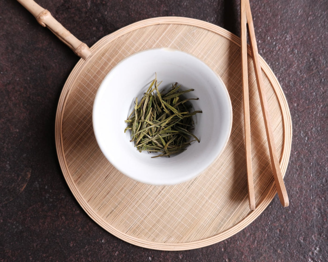 Anjibaicha Chinese green tea from Zhejiang, China, in infused loose-leaf with white porcelain gaiwan teaware from Jingdezhen, green bamboo coaster and bamboo clamps