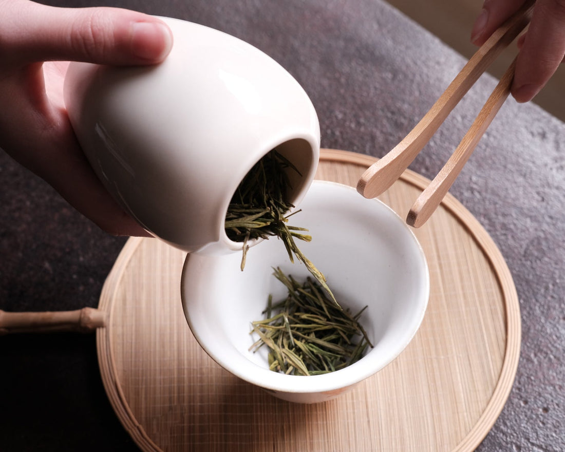 Anjibaicha Chinese green tea from Zhejiang, China, in dry loose-leaf from a Dehua ceramic vase with white porcelain gaiwan from Jingdezhen and green bamboo coaster