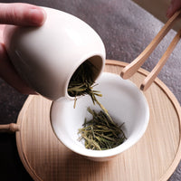 Anjibaicha Chinese green tea from Zhejiang, China, in dry loose-leaf from a Dehua ceramic vase with white porcelain gaiwan from Jingdezhen and green bamboo coaster