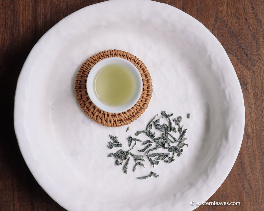 Chinese green tea from Yunnan, Dianlu, loose-leaf with white porcelain cup and coaster from Jingdezhen - dry leaves detail