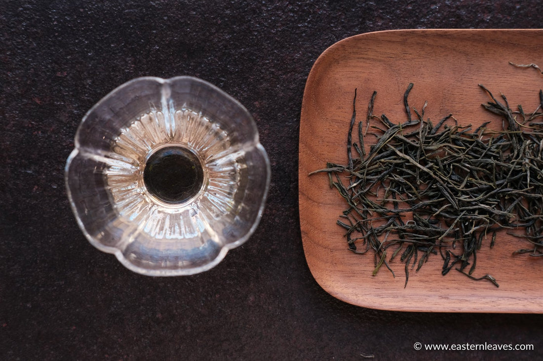 Chinese green tea Enshiyulu, steamed dry loose-leaf on wooden tray, bright transparent infusion in glass cup