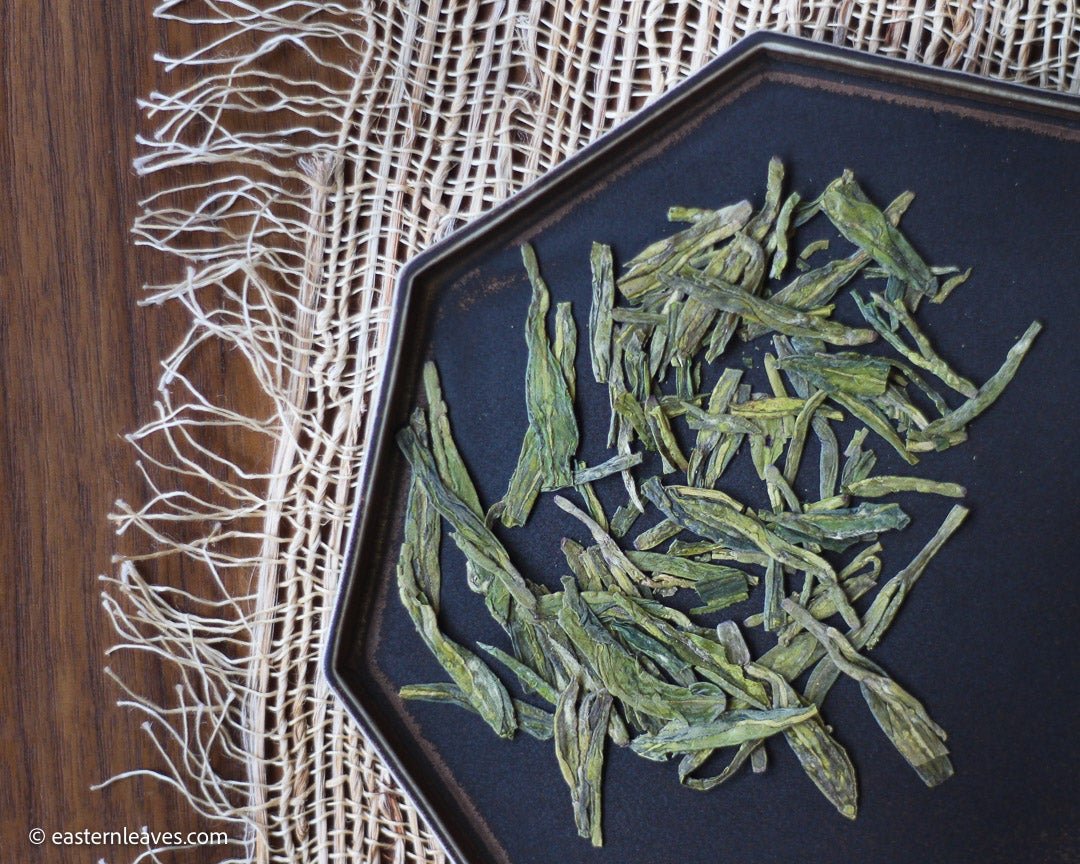 Longjing from Xihu Meijiawu, cultivar 43 Chinese green tea pre-rain, loose-leaf on black tray from Dehua, China